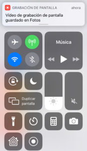Modal del Centro de control, en donde el botón para grabar la pantalla de tu iPhone fue presionado para detener la grabación. Se observa una notificación diciendo que la grabación fue guardada en la app de Fotos.