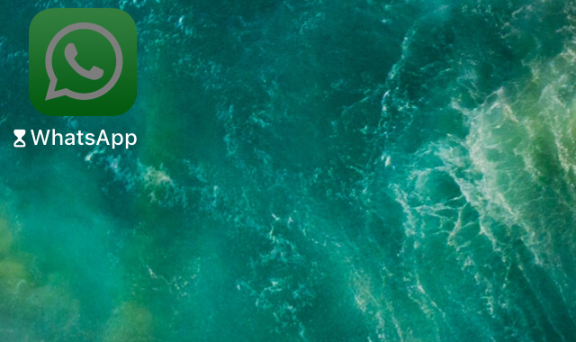App de WhatsApp en el menú principal de un iPhone. Se observa que el color del icono de la app es más oscuro de lo usual, y también se observa un icono de un reloj de arena al lado del nombre de la app.