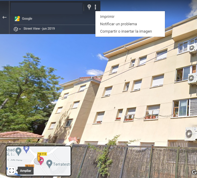 Imagen satelital de Street View de Google Maps mostrando una ventana pequeña con la dirección de un edificio (censurada en la imagen). Se observa un menú en esa ventana con la opción “Notificar un problema”.