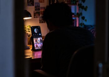 Persona desconocida observando clandestinamente un perfil de TikTok desde una habitación oscura