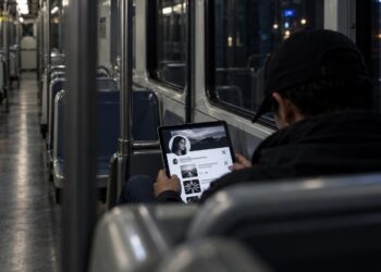 Persona desconocida consultando en secreto el perfil de X de otra persona en un vagón nocturno