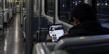 Persona desconocida consultando en secreto el perfil de X de otra persona en un vagón nocturno