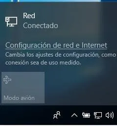 Icono de un ordenador en la barra de tareas de un PC, y el enlace “Configuración de red e internet”.