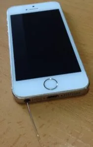 iPhone con una aguja de coser dentro del puerto de los auriculares.