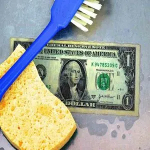 Billete siendo lavado con un cepillo y una esponja.